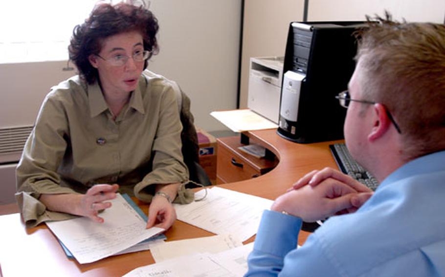 Cristina Bowers, one of 19 volunteer translators at the family readiness center, helps Nick White, housing program manager for Vicenza, Italy, write a letter to a local telephone company.