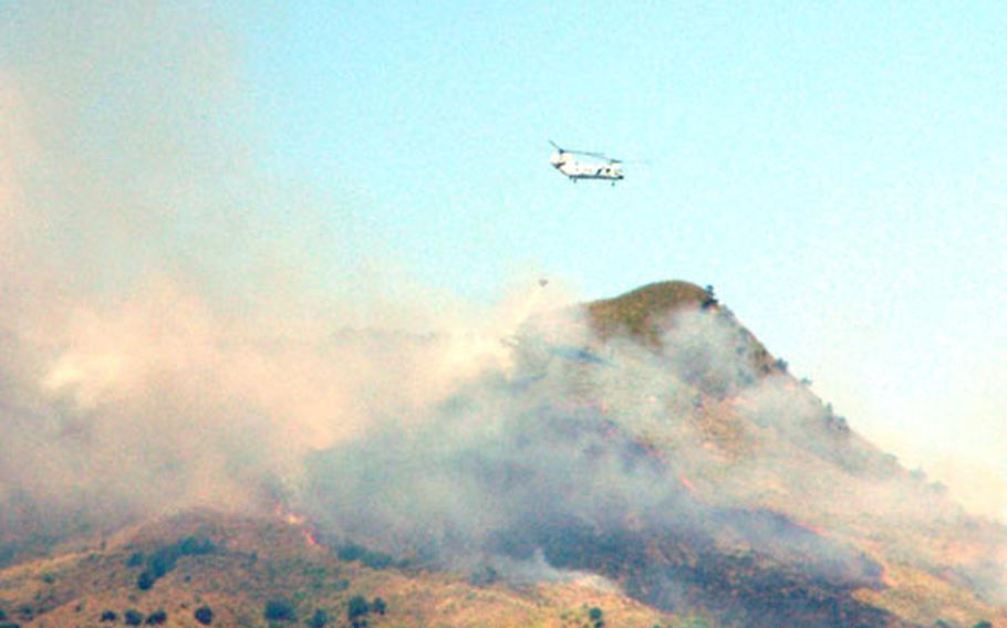 A Marine CH-46 helicopter dumps a load of water Tuesday on a brush fire on Camp Hansen, Okinawa, that began Monday afternoon and had burned nearly 300 acres by Tuesday afternoon.