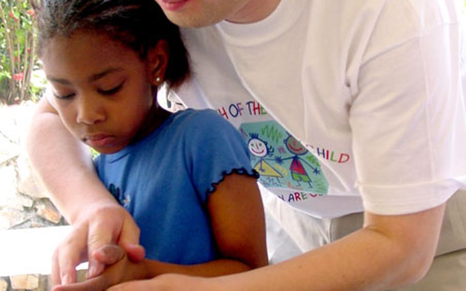 Kim Song-min, a prevention specialist with the Army’s Area IV Family Advocacy Program, helps fingerprint Kyana Goodman, a Taegu American School kindergartner, at Camp George in Taegu, South Korea.