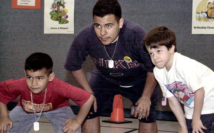 Adrian Emmet, a ninth-grader at Ramstein High School, crouches down with a couple of elementary school students last month during a game they played together. A program started last year puts high school and elementary school students with deployed parents together to have fun.