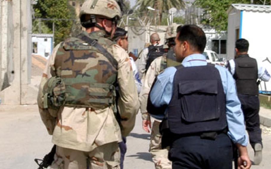 Four U.S. soldiers from Delta Company, 464th Armor Battalion of the 3rd Infantry Division, walk along the streets of Baghdad's International Zone with a four-man squad of Iraqi police during a joint patrol Tuesday.
