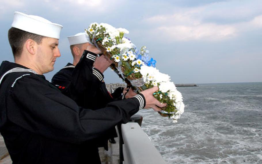 Petty Officer 2nd Class Paul Dinkins, a cryptologic technician with the Naval Security Group Activity at Naval Air Facility Misawa, Japan, gets ready to toss a wreath of flowers into the Pacific Ocean during a ceremony Friday in Misawa to honor the 31 servicemembers killed aboard an EC-121 shot down by North Korean fighter jets 36 years ago.