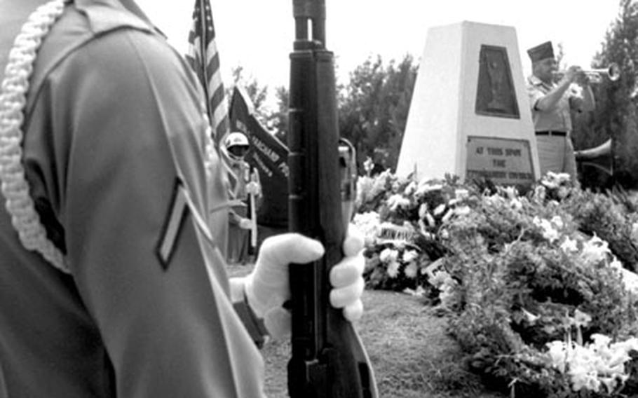 A member of the firing squad from 2nd Battalion, 503rd Infantry, 173rd Airborne Brigade stands at attention as Pfc. Henry Smolak plays taps at the memorial service for Ernie Pyle.