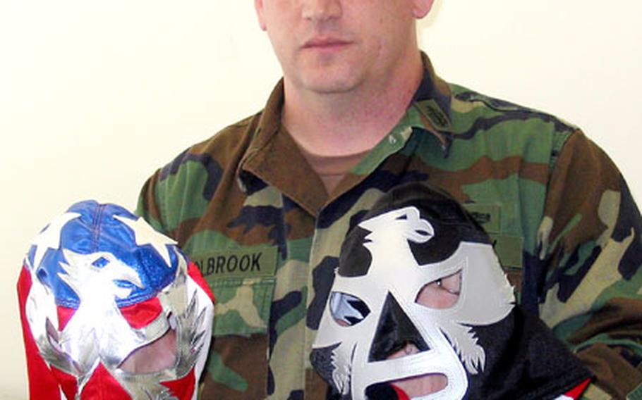 Senior Chief Petty Officer Glen Holbrook, a master-at-arms at Sasebo Naval Base's Security Division, shows two of the masks he's worn as a longtime professional wrestler. He started at age 20 in Georgia, and still wrestles as a "bad guy" in Japanese pro matches.