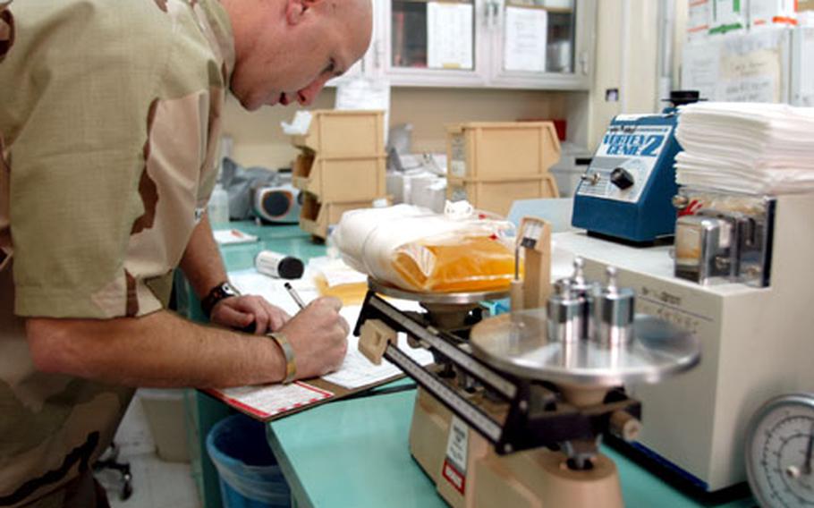 Spc. James Barnes, a lab technician, weighs and records a bag of platelets collected Saturday at the 86th Combat Support Hospital collection center in Baghdad, the only platelet collection center in Iraq.