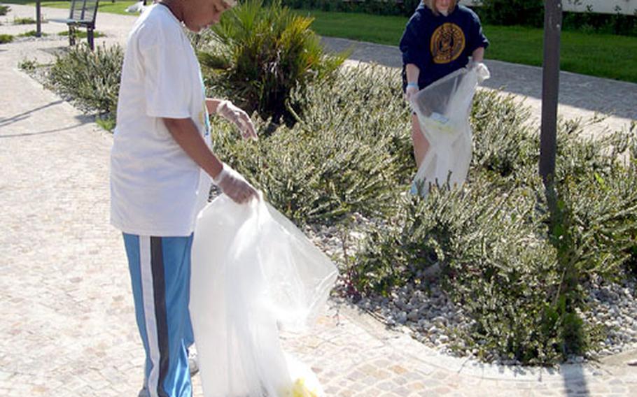 Classmates Kendall Olinger, right, and Channda Mitchell walk along one of the walkways leading between the apartment buildings at the Naval Support Activity Naples, Italy, Gricignano housing area. The small, green shrubs caught lots of trash, and the girls spent much of the late morning bent over picking it up during the base's annual Earth Day commemoration.
