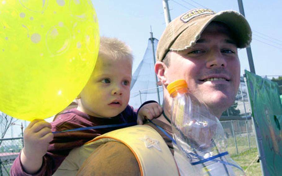 Fifteen-month-old Korvin Lalumia peeks around his father, Staff Sgt. Clancy Lalumia, during the Community Fun Fair held Saturday at the Child Development Center at Yongsan Garrison, South Korea.