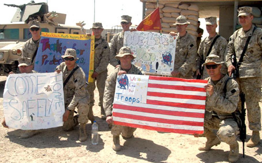 Marines display banners and messages sent from their hometowns. In back row are Cpl. Keith Richardson, 21, Cpl. Andy Aranda, 22, Cpl. Wade Scott, 22, Cpl. Jarrod Bowers, 21, Cpl. Stephen Cornish, 29, Cpl. Nolan Ruby, 22. In the bottom row from left to right are Cpl. Nicholas Mentges, 26, Sgt. Christopher Rosetti, 26, Sgt. Daniel Blackwell, 29, and Cpl. Daniel Nichols, 29.