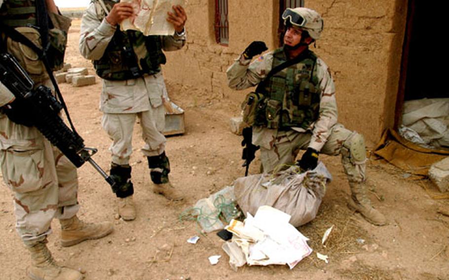 Sgt. Erik Griffin, kneeling, empties the contents of a bag found Friday in what could be an abandoned house in Tal Abtha, Iraq. While the bag contained medical IV bags, some wiring, identification cards and schoolbooks, nothing seemed suspicious, Griffin said.