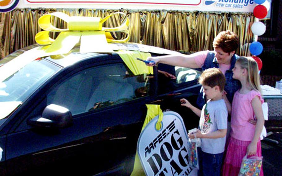 Peggy Clark and her children, Hunter and Kalah, cut the ribbon off a new Mustang Friday morning. The three, along with dad Staff Sgt. Lyn Clark, won a new Ford Mustang in the Burger King/AAFES "Dog Tag Drill Call" game. They have special-ordered their own Mustang for delivery around November.
