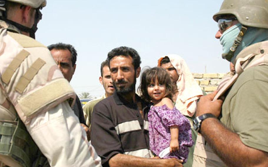 Staff Sgt. Timothy Hooper, 25, of New Orleans, left, interviews Iraqis who saw a carload of people plant a roadside bomb in Baghdad Friday afternoon. Man at right is an interpreter.