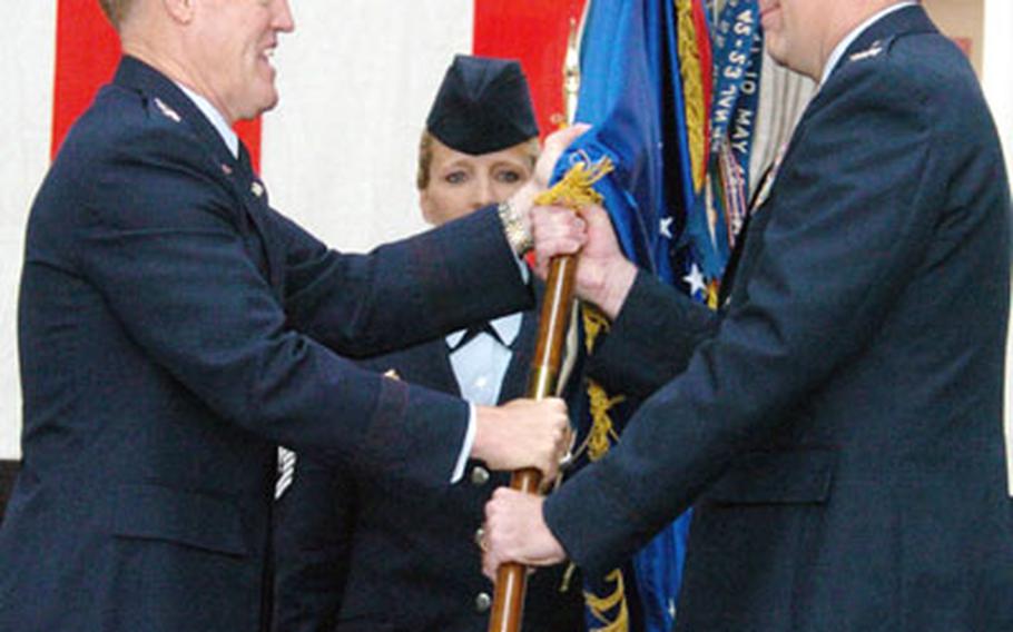 Lt. Gen. Bruce A. Wright, left, passes the wing guidon to Col. Scott P. Goodwin as Goodwin assumes command of Yokota Air Base in a change of command ceremony Wednesday.