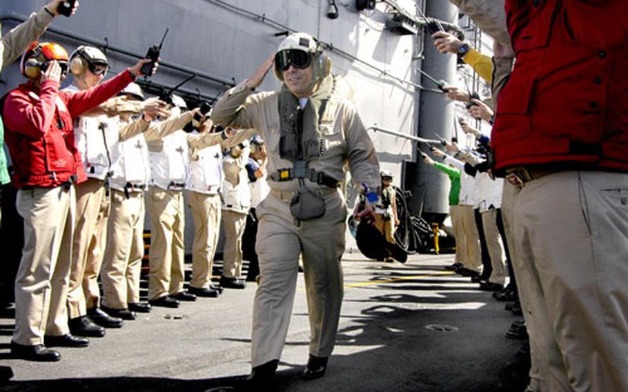 Capt. Samuel Perez Jr. is rendered honors by members of the USS Kitty Hawk’s wardroom Thursday as he departs the Kitty Hawk for the final time as the outgoing commodore of Destroyer Squadron 15.