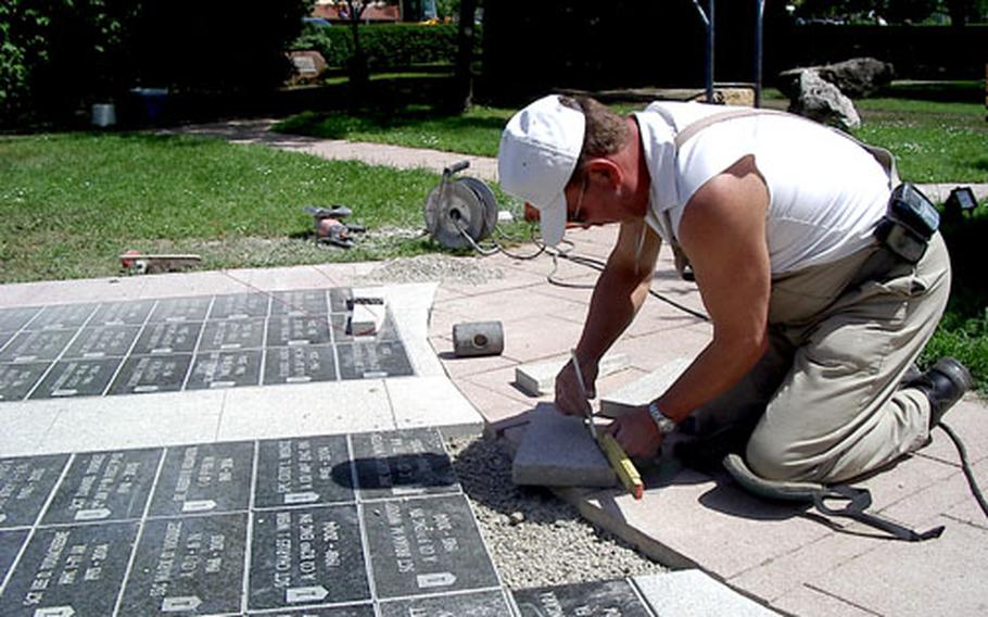 Otto von Hausen, a German base support battalion worker, puts the finishing touches on a sidewalk of memorial stones at the foot of the fallen soldiers monument.