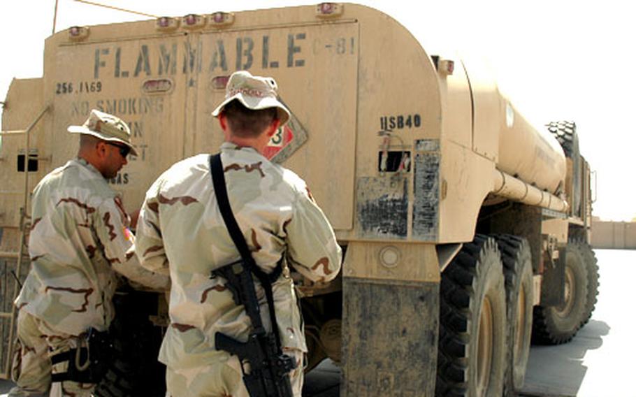 Capt. Augusto Villalaz, 35, of Lake Charles, La., left, and E5 Rock Weatherly, 44, of Perrysville, Ind., check a fuel truck on Sunday afternoon at Camp Independence. Villalaz said he learned that Iraqi officers were buying truck fuel for missions with their own money because of a delay with contacts between vendors and the Iraqi Ministry of Defense. Villalaz helped arrange for 2,400 gallons of fuel for the Iraqi soldiers he works with at the camp. But U.S. officers want the Iraqi army to become less dependent on U.S. means and might.