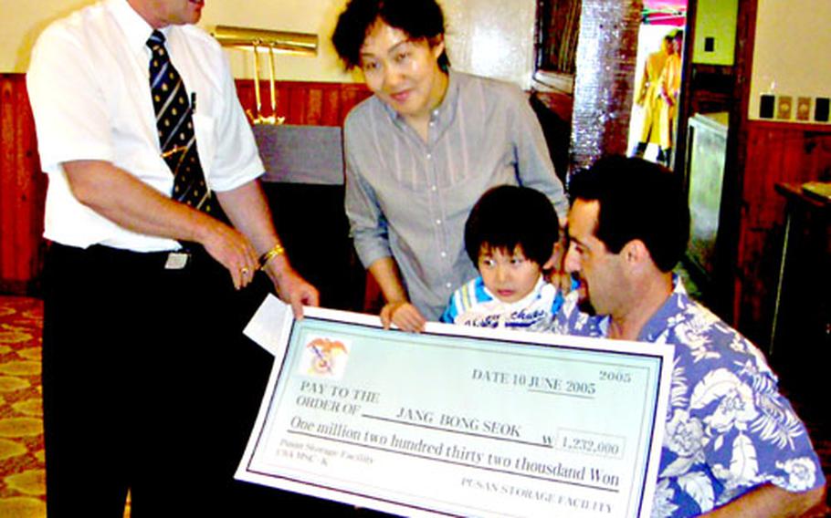 John Batchelor, left, deputy commander of the Army’s Pusan Storage Facility in South Korea, on Friday presents a mock-up of the check donated to help Jang Bong-sok, 5, center, get hearing-aid implant surgery. Center left is Sister Catarina. At right is Anthony Gray, who also helped raise money.