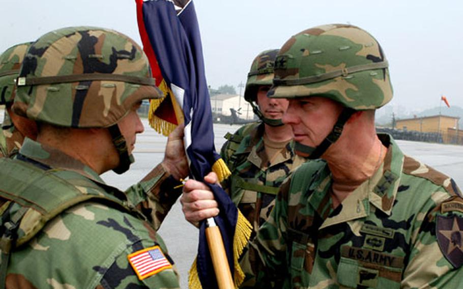 Second Infantry Division commander Maj. Gen. George A. Higgins, right, hands the Aviation Brigade colors to new Multi-Functional Aviation Brigade commander Col. Peter W. Foreman while outgoing Aviation Brigade commander Col. Thomas De Vine, second from right, looks on at Camp Casey, South Korea, on Tuesday.