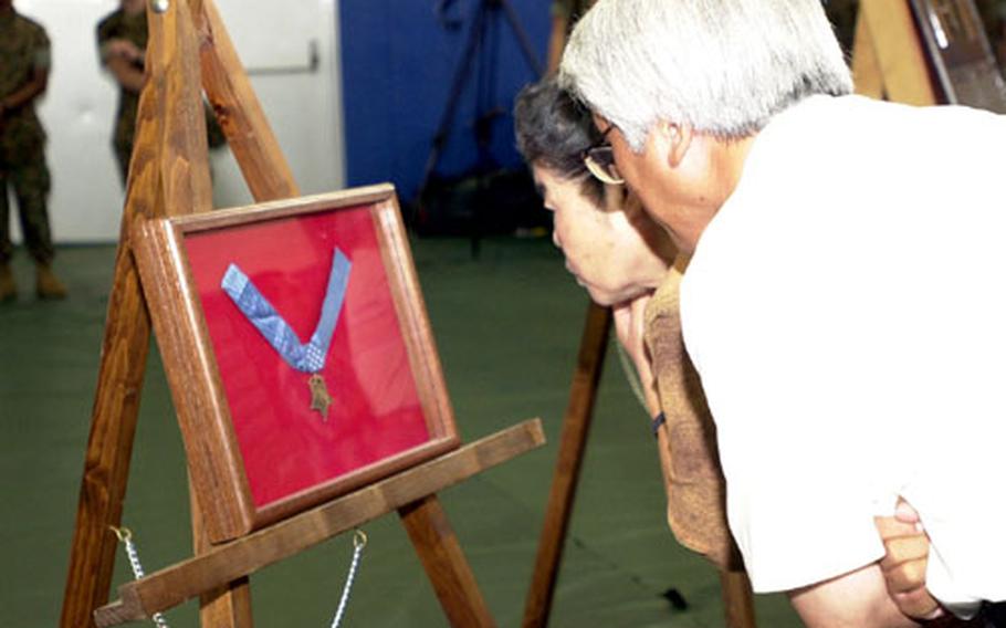 Okinawans look at the replacement Medal of Honor dedicated in memory of Pfc. Albert E. Schwab.