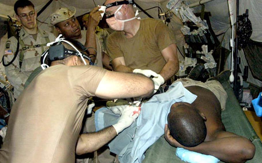 Drs. (Maj.) Imad Haque, back to camera, and (Lt. Col.) Mike Dye on Wednesday operate to remove a fatty growth from the arm of Sgt. Maj. Abdoulaye Ahamat of the Nigerien army. Standing to the left is Capt. Steve Schmelzer. Wiping Dye’s brow is Staff Sgt. Eric Gregory.