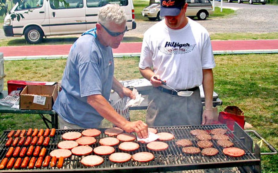 Sasebo Naval Base’s Morale, Welfare and Recreation department’s Walter Birkenheier, left, and librarian Wayne Newnan work the grill Friday at the annual Volunteer Appreciation Picnic in Nimitz Park.