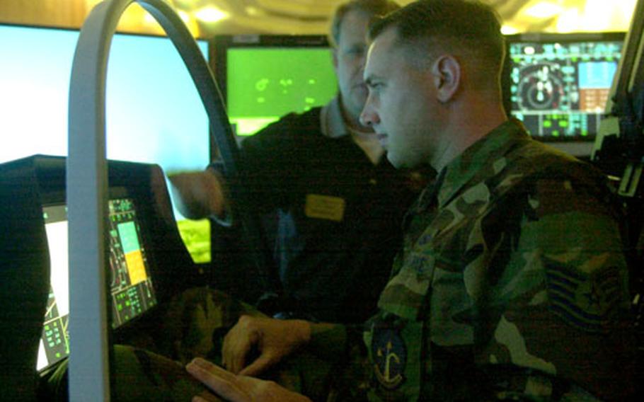 Rob Bennett, F-35 Joint Strike Fighter vehicle interface engineer and Navy Reserve pilot, back, shows an Air Force airman at Spangdahlem Air Base, Germany, how the F-35 Joint Strike Fighter simulator works.