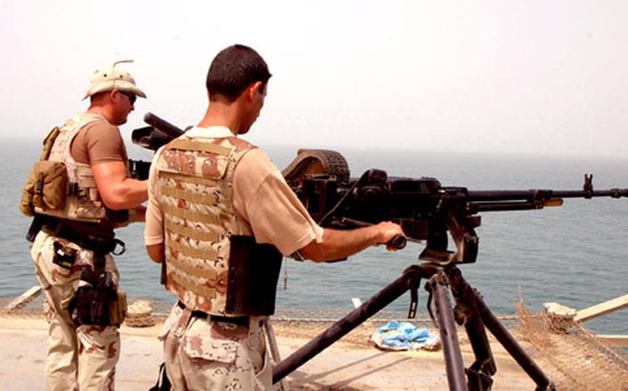 An Iraqi sailor armed with a .50-caliber machine gun joins Petty Officer 2nd Class Michael Myers for security duty aboard an oil platform off the coast of Basra, Iraq.