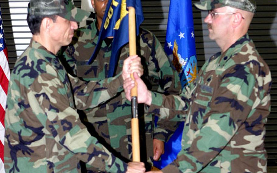 New 607th Support Squadron commander Lt. Col. Mark A. Aicher, right, accepts the guidon from Col. Edward Acevedo, commander of the 607th Air Support Group. At center is Master Sgt. Robert Gordon.