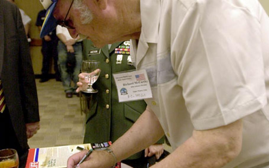 Former Army Pfc. Richard McCarthy signs a Battle of Okinawa Historical Edition G.I. Joe at Torii Station, Okinawa, on Wednesday.