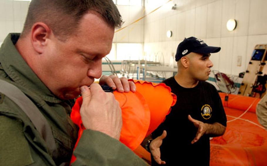 Lt. Col Bill Summers inflates his flotation device manually as instructor Sgt. Dave Jewell explains what to look out for when trying to survive in the water.
