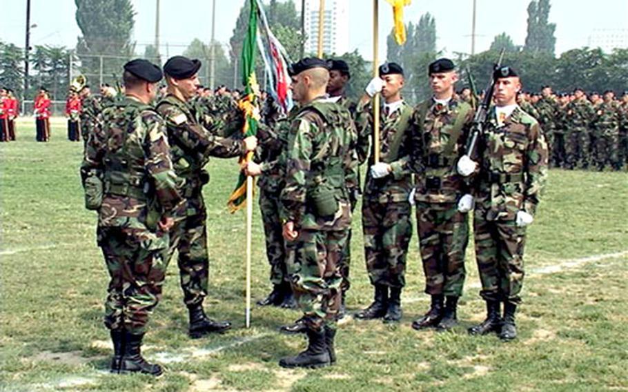 Lt. Col. Douglas L. Ingros hands the 728th Military Police Battalion’s guidon to battalion commander Command Sgt. Maj. Norman Hampton at a change-of-command ceremony Friday at Camp Walker, South Korea. Ingros replaces Lt. Col. Steven L. Crowe, standing right and facing Ingros, who is retiring.