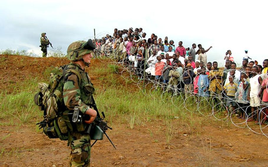 Marines watch refugees moving along a concertina wire in Liberia in August 2003. Nearly one-third of the U.S. personnel who landed were treated for malaria.