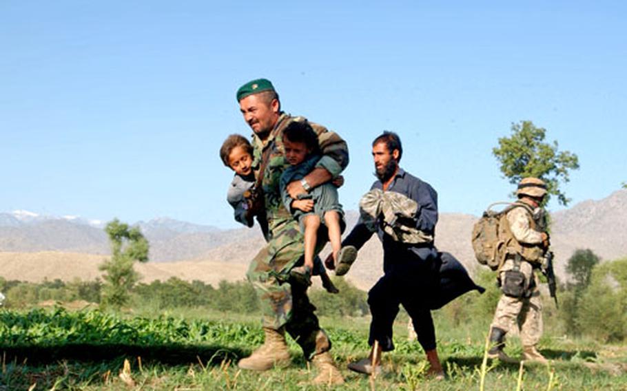 An Afghan army soldier rushes children to a waiting helicopter on June 23 in Lagham Province, Afghanistan. More than 119 people were stranded by the rising flood waters of the Indus River in the province. Soldiers from the Afghan army, as well as coalition troops and aid agencies worked together for the rescue operation when a dam upstream broke.
