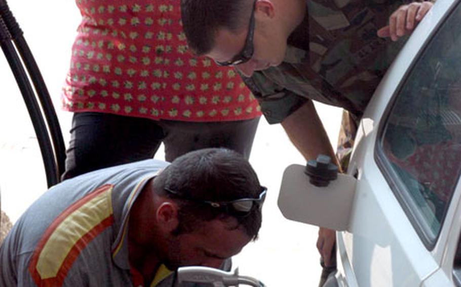 Tech. Sgt. Jason Farmer watches as Giancarlo Dall’Acqua puts some air in his tires Tuesday at the Agip station outside the gates of Aviano Air Base, Italy. Milvia Dall’Acqua waits to put gas into Farmer’s car. That gasoline will be a bit cheaper for Americans in Italy starting next month, even as pump prices rise for Italians.