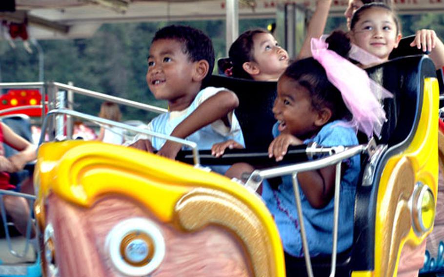 B.J. Lewis, 5, foreground left, and his sister Naomi, 4, enjoy a roller coaster ride with Kira Merrill, 3, background left, and her sister, Sarah Merrill, 6, at a prior July 4th celebration at Carney Park in Naples, Italy.