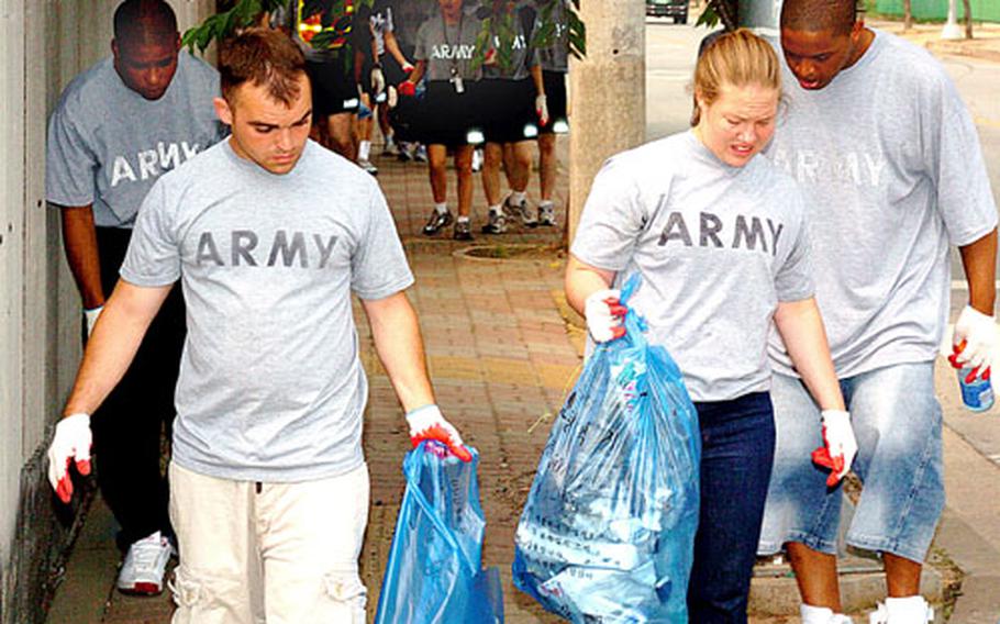 Soldiers from Camp Humphreys carry trash they've collected on streets of the Anjung-ri section outside the post.