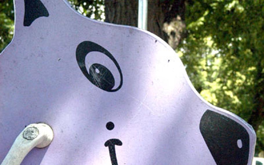 A hobby-horse stands underneath a sign warning that lead-based paint had been found on a nearby jungle gym in a residential playground at the Grafenwöhr, Germany, training area.