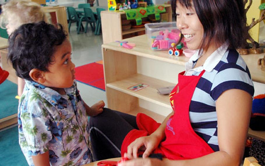 Eriko Elmoutawakel helps Malic Clark, 2, during playtime Thursday at Sasebo Naval Base’s Child Development Center on the main base. The CDC still has openings for two full-time positions and several flex-time slots. Administrators also are encouraging spouses to start home child-care businesses.