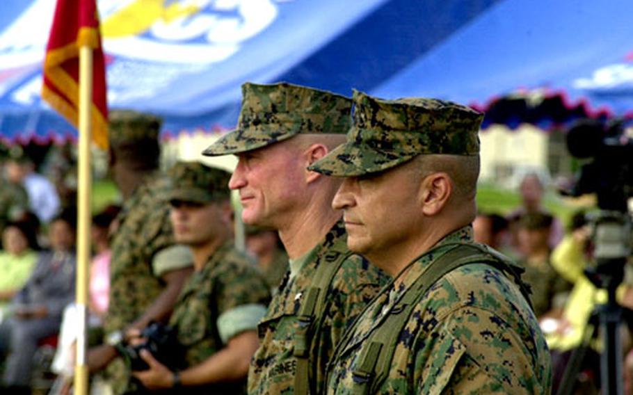 Brig. Gen. James Flock, left, and Brig. Gen. Joseph Medina watch a flag presentaion Friday at Camp Foster, Okinawa, as Medina replaces Flock as commander of all Marine bases on Okinawa.