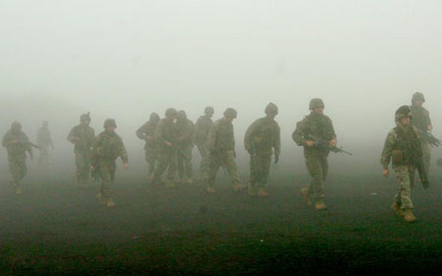 Marines walk to their training positions Saturday morning under a layer of fog at Camp Fuji, Japan. They’re training airmen from Yokota Air Base for an upcoming transport mission in Iraq.