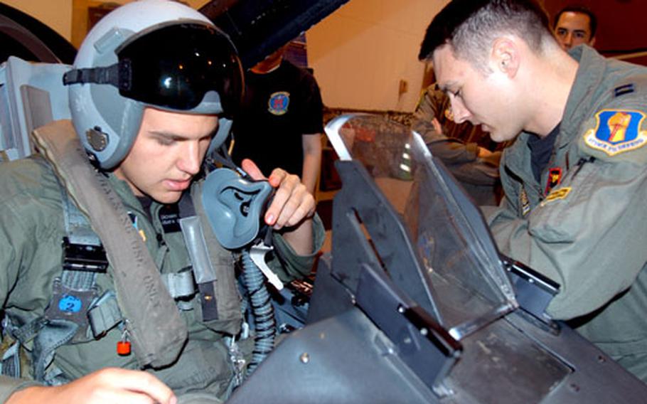 Capt. Tim Nauroth, a 14th Fighter Squadron pilot, right, helps Air Force Academy cadet Zachary Carey strap into an F-16 egress trainer Monday at Misawa Air Base, Japan. As part of a summer internship program, 17 academy cadets are visiting Misawa.