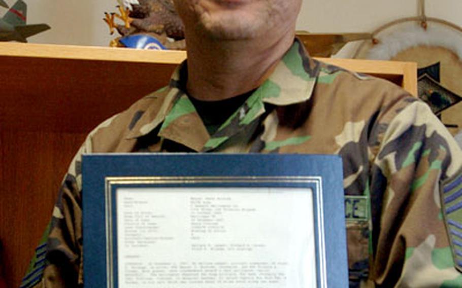 Air Force Chief Master Sgt. Marc Rodriguez, wearing the POW/MIA bracelet, holds the biographical information of the person his bracelet honors, Army Staff Sgt. Manuel J. Moreida.