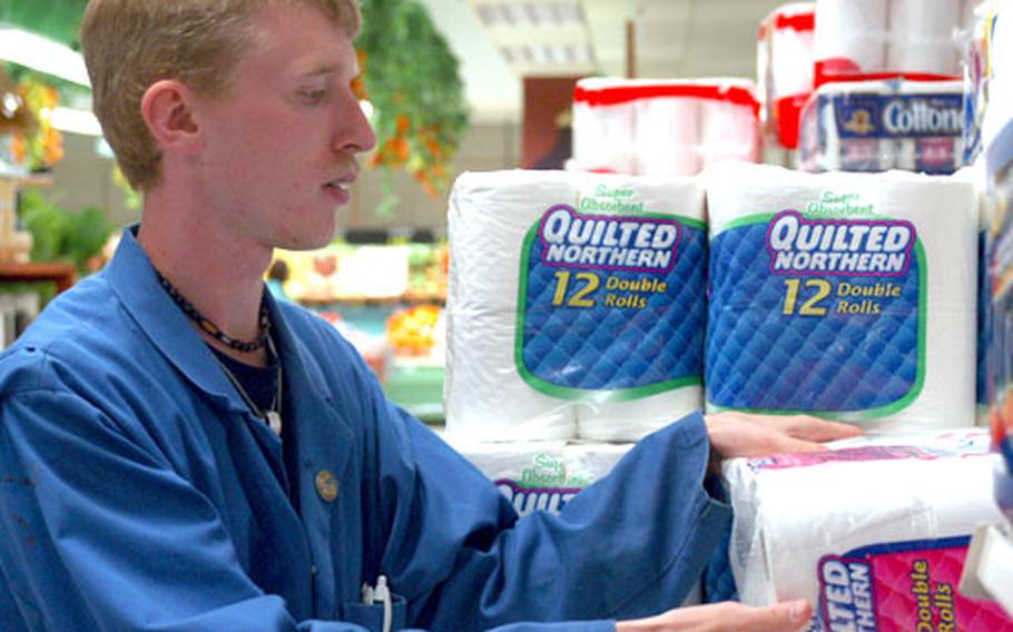 Chris Ray, 19, rearranges a sales display at the front of the Vilseck, Germany, commissary Tuesday. A veteran of the commissary agency's student hire program, Ray decided to stick with the work after graduation this year and now has a part-time position at the store.
