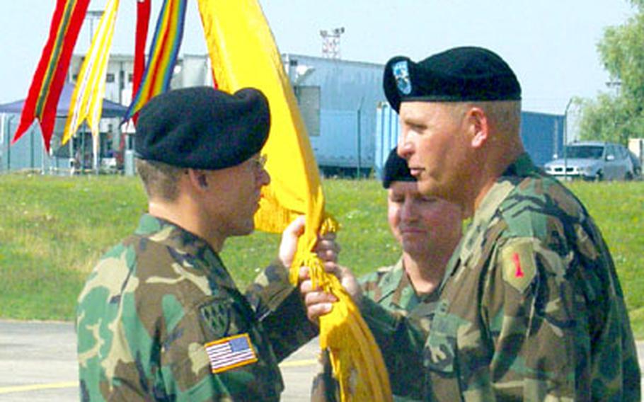 1st Infantry Division commander Maj. Gen. Kenneth Hunzeker, right, hands the 69th Air Defense Artillery battle flag from the outgoing commander, Col. R. Kirk Lawrence, middle, to the new commander, Col. Mark McConkey, during a ceremony Thursday.
