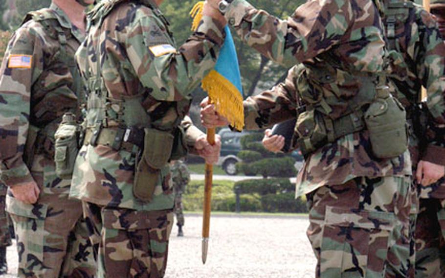 Col. Timothy K. McNulty, right, passes the unit colors to Brig. Gen. H.T. Landwermeyer, Jr., commander of the Korea Region of the Installation Management Agency Thursday, while Col. Ronald C. Stephens, left, watches.