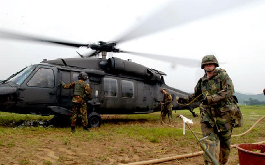 From left, 2-2 Black Hawk crew member Spc. Dennis Sharek waits while fuelers Joe Bell and Spc. Nicole Mabury pump gas and ground the helicopter to prevent static electricity discharges.