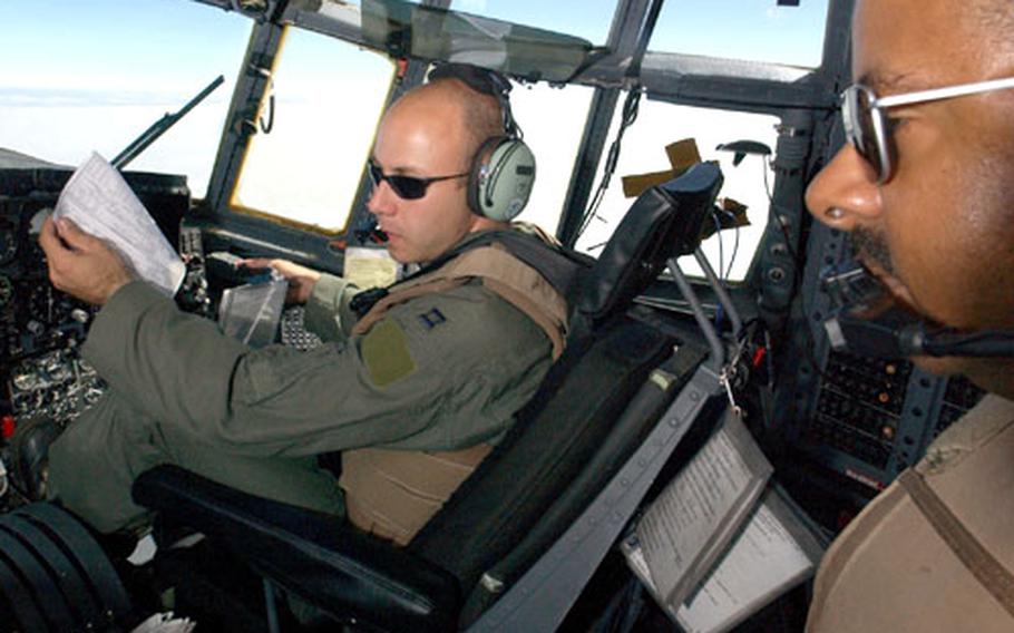 Capt. Robert Lewis, co-pilot, and Tech. Sgt. Harry Brown, the navigator, review the map on a C-130 out of Ramstein Air Base, Germany, en route from Kigali International Airport in Rwanda to Sudan. Lewis and Brown are both with the 86th Air Expeditionary Group.