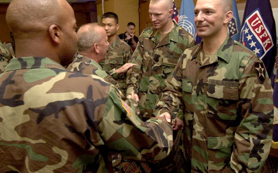 Staff Sgt. Thomas A. Bean Jr., far right, Pfc. Robert A. Wallace, center, and Cpl. Kim Jung-tak, partially obscured, accept congratulations after an award ceremony Monday at Yongsan Garrison, South Korea.