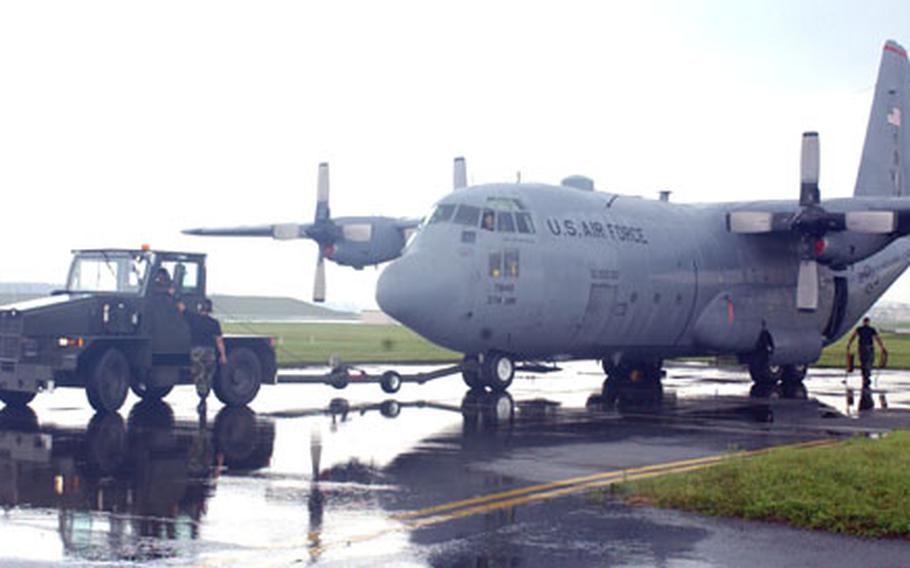 Senior Airman Ray Pontemayor, 374th Aircraft Maintenance Squadron crew chief, discusses the towing of a C-130 Hercules as another crew chief removes the chocks Monday at Yokota Air Base, Japan. The base’s C-130s were relocated as Tropical Storm Banyan approached the Kanto Plain.