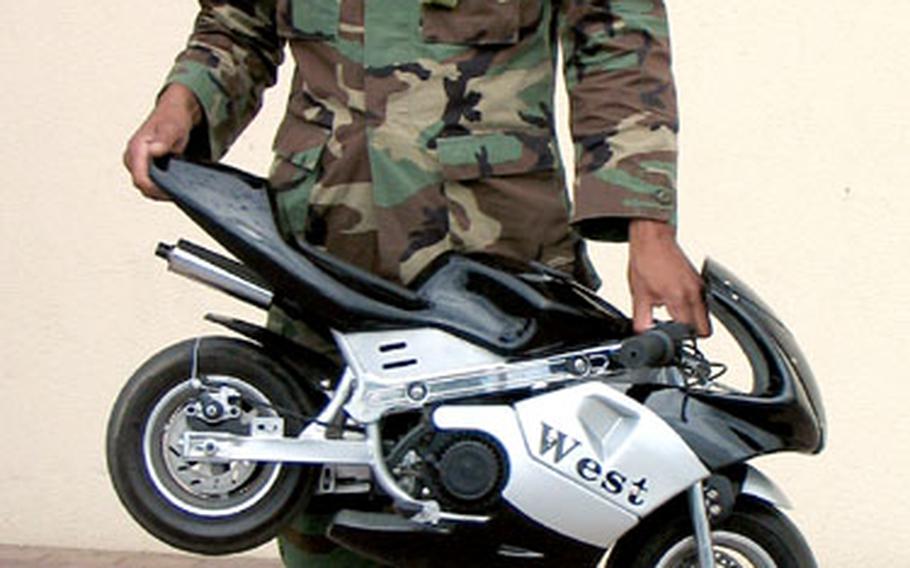 Staff Sgt. Mark Pratorius, a military policeman, holds his pocket bike in front of the Bamberg military police station.