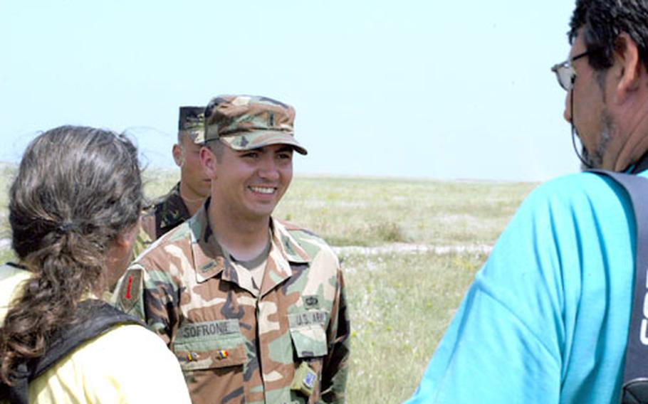 First Lt. Mihai Sofronie, with the 177th Armored Battalion, 2nd Brigade out of Schweinfurt, Germany, speaks with Romanian journalists in Babadag Training Area, Romania, on Sunday. Sofronie, who was born in Romania, serves as a personal aid to the ROMEX ’05 commander.